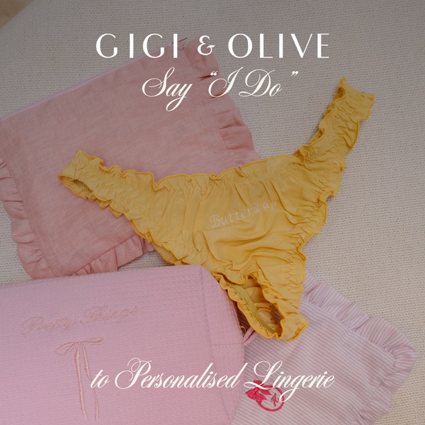 A high-end flat lay photograph featuring embroidered personalised lingerie and matching accessories in soft pastel tones.